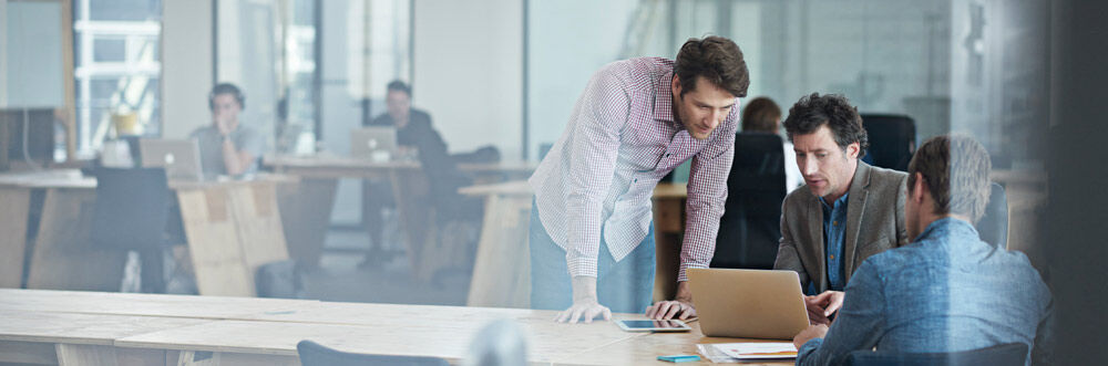 Colleagues working together around a computer in an office